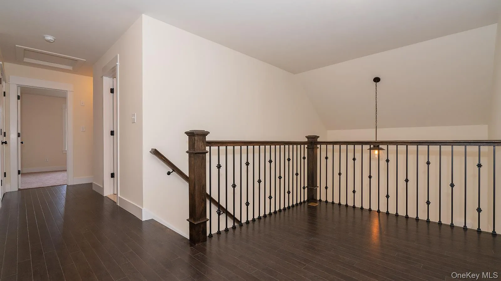 Corridor with lofted ceiling, dark wood-style floors, and an upstairs landing Corridor with lofted ceiling, dark wood-style floors, and an upstairs landing