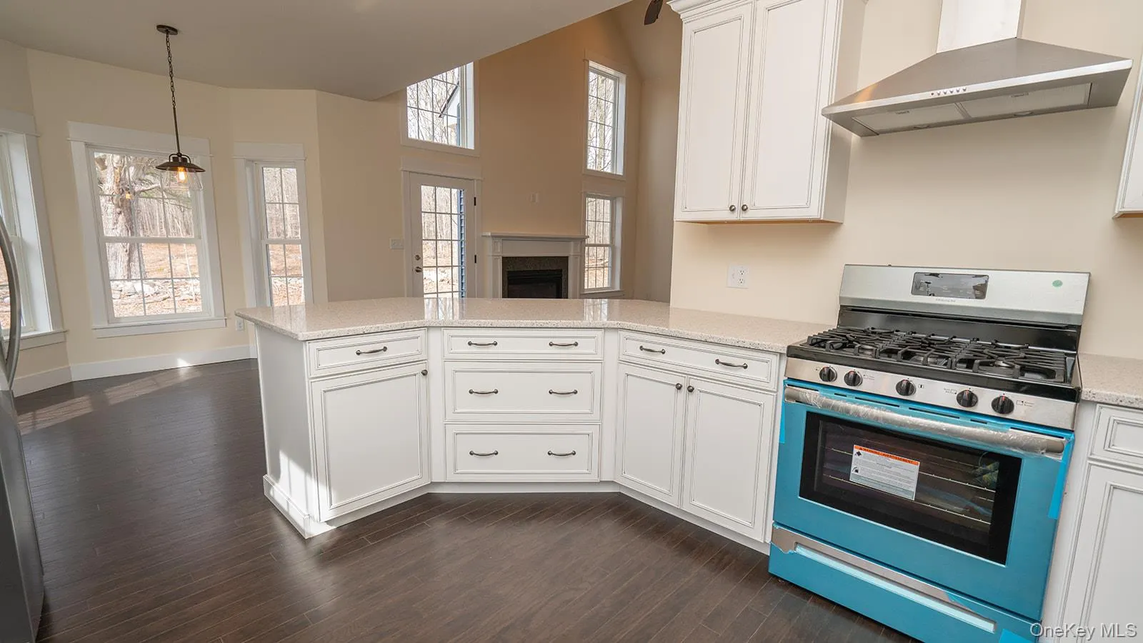 Kitchen featuring appliances with stainless steel finishes, wall chimney range hood, white cabinets, a peninsula, and dark wood-type flooring Kitchen featuring appliances with stainless steel finishes, wall chimney range hood, white cabinets, a peninsula, and dark wood-type flooring
