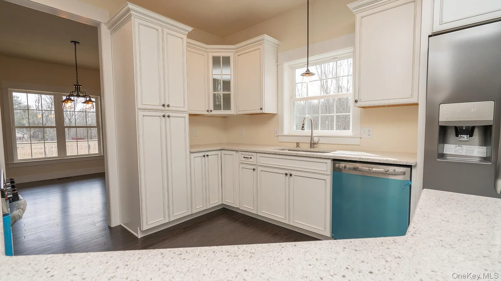 Kitchen featuring stainless steel fridge with ice dispenser, dishwasher, glass insert cabinets, a chandelier, and hanging light fixtures Kitchen featuring stainless steel fridge with ice dispenser, dishwasher, glass insert cabinets, a chandelier, and hanging light fixtures