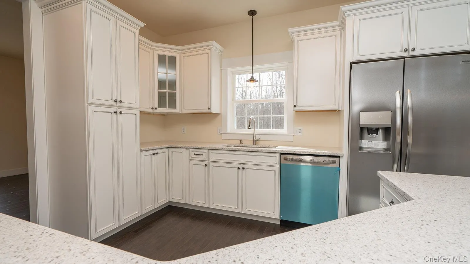 Kitchen featuring stainless steel fridge, dishwashing machine, white cabinetry, decorative light fixtures, and glass insert cabinets Kitchen featuring stainless steel fridge, dishwashing machine, white cabinetry, decorative light fixtures, and glass insert cabinets