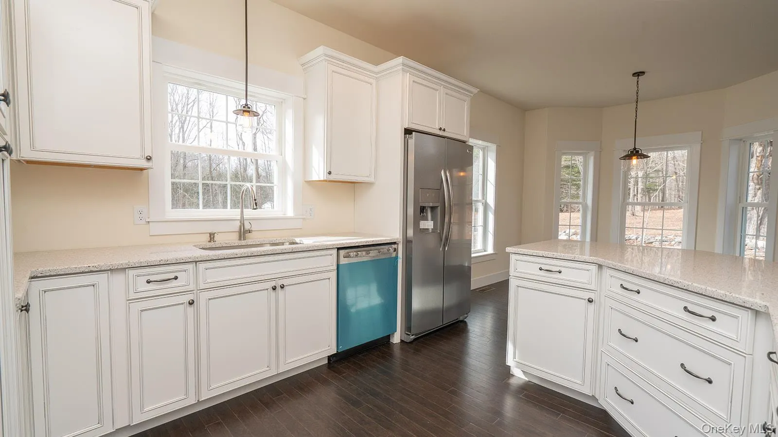 Kitchen featuring white cabinetry, stainless steel fridge with ice dispenser, pendant lighting, and dishwashing machine Kitchen featuring white cabinetry, stainless steel fridge with ice dispenser, pendant lighting, and dishwashing machine
