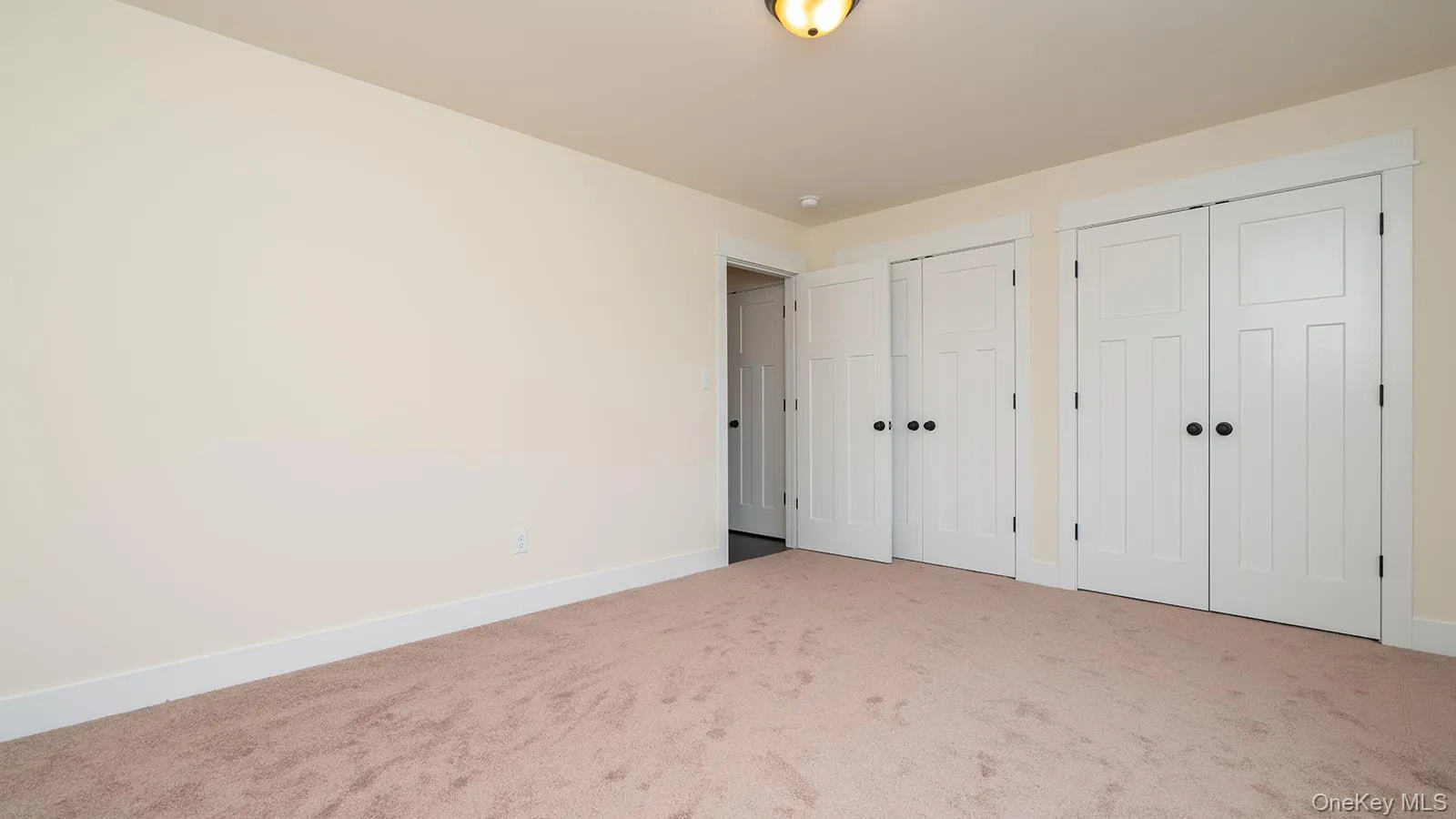Unfurnished bedroom featuring multiple closets and carpet flooring Unfurnished bedroom featuring multiple closets and carpet flooring