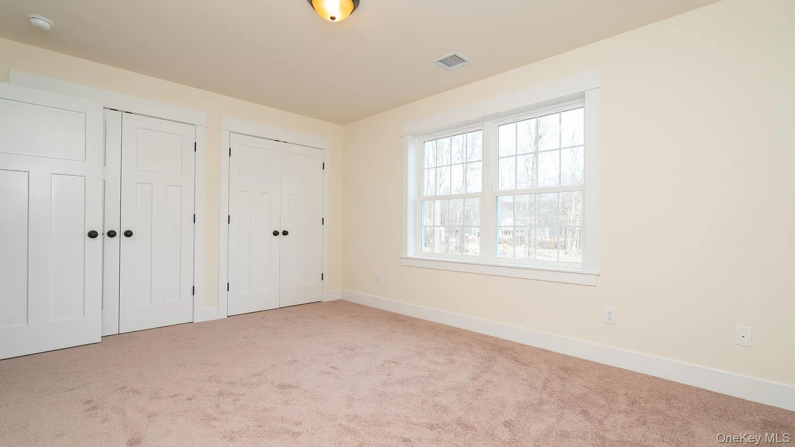 Unfurnished bedroom featuring multiple closets and light colored carpet Unfurnished bedroom featuring multiple closets and light colored carpet