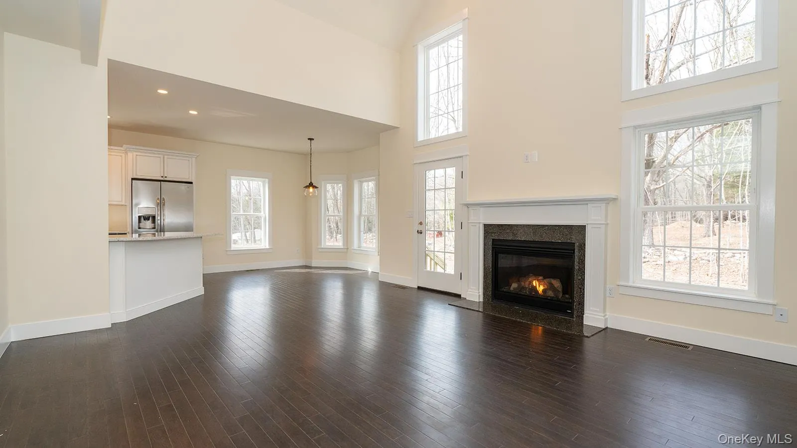 Unfurnished living room featuring dark wood-style flooring, a high end fireplace, recessed lighting, and a high ceiling Unfurnished living room featuring dark wood-style flooring, a high end fireplace, recessed lighting, and a high ceiling