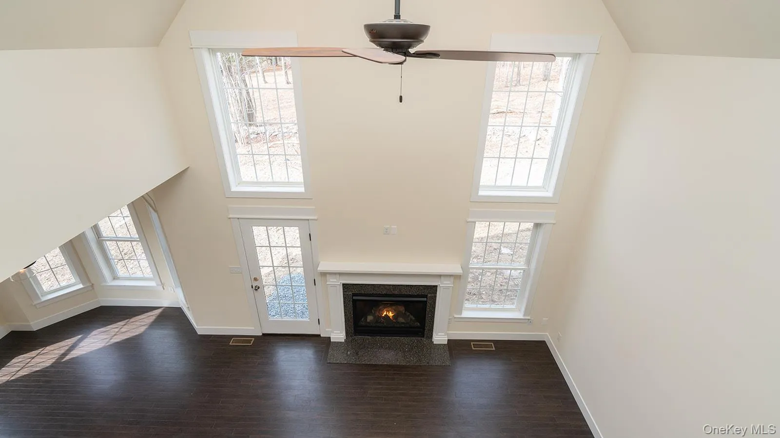 Unfurnished living room featuring high vaulted ceiling, dark wood-style floors, a high end fireplace, and plenty of natural light Unfurnished living room featuring high vaulted ceiling, dark wood-style floors, a high end fireplace, and plenty of natural light