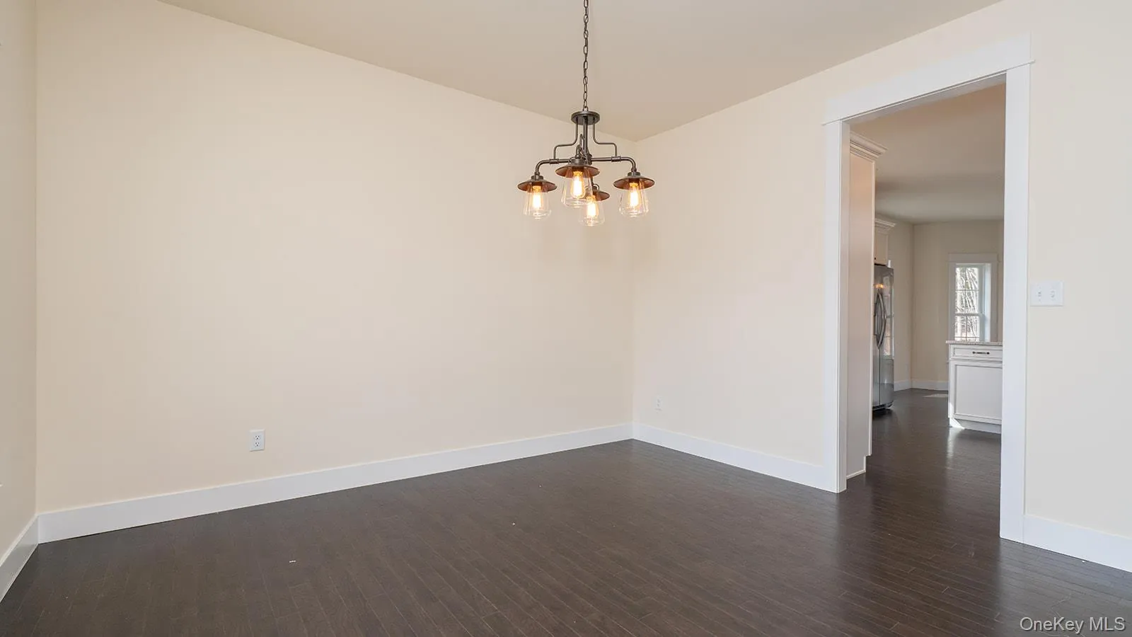 Spare room with dark wood-type flooring and a chandelier Spare room with dark wood-type flooring and a chandelier