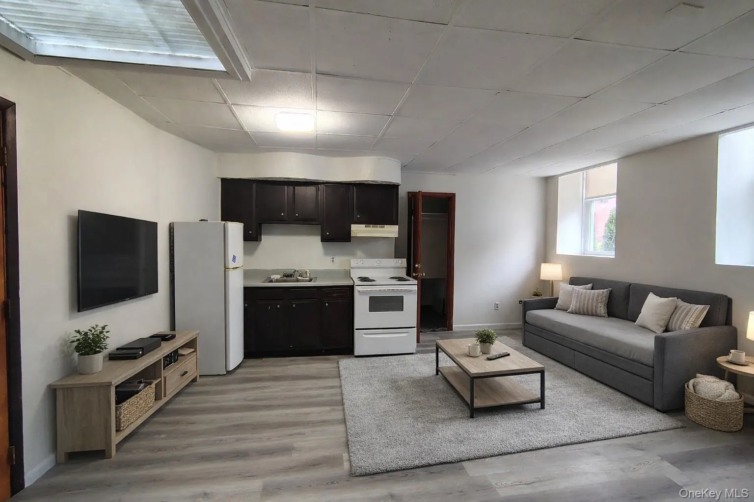 Living area featuring light wood-type flooring and a paneled ceiling Living area featuring light wood-type flooring and a paneled ceiling
