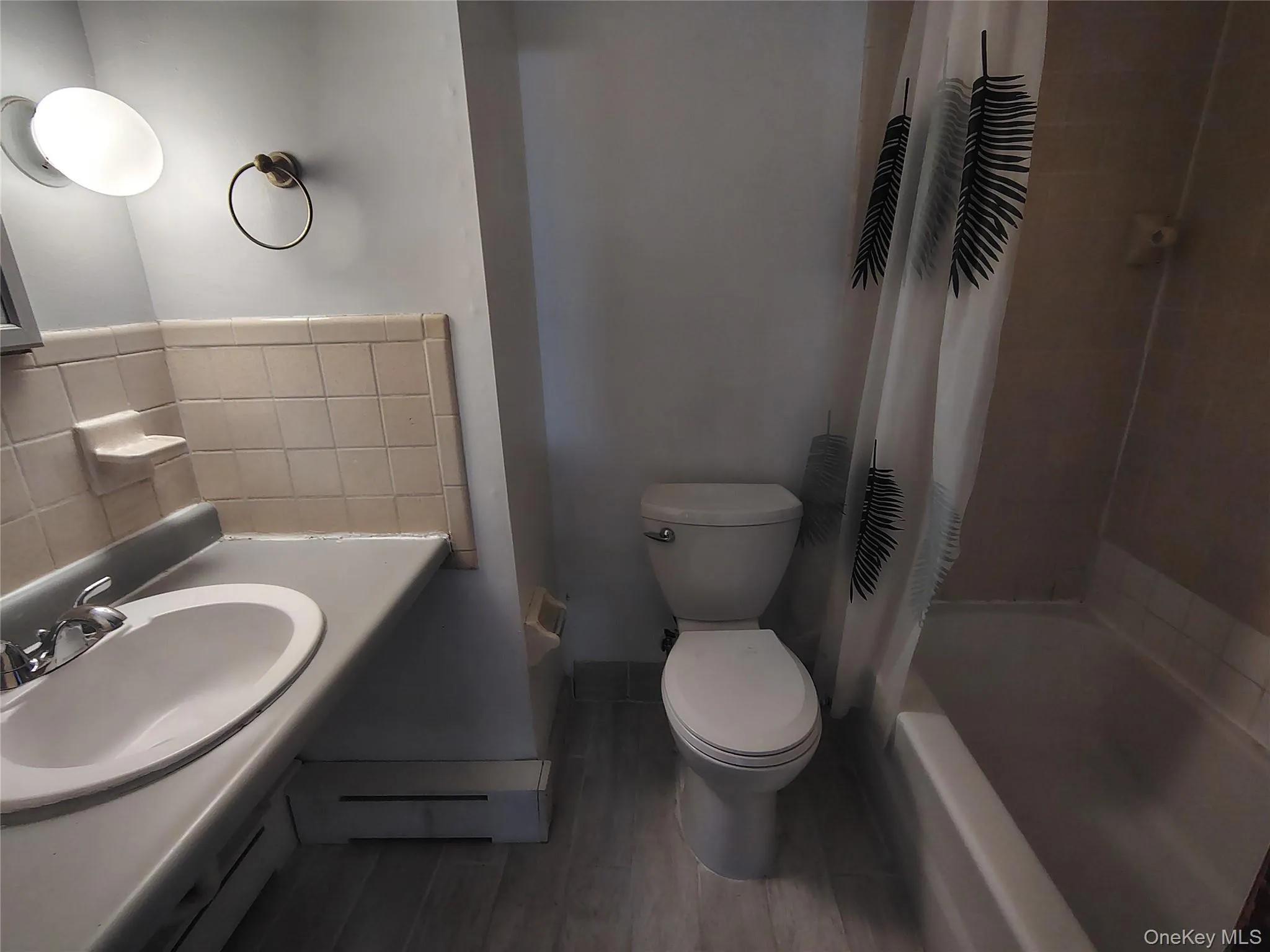Full bathroom with shower / bathtub combination with curtain, wood finish floors, baseboard heating, and vanity Full bathroom with shower / bathtub combination with curtain, wood finish floors, baseboard heating, and vanity