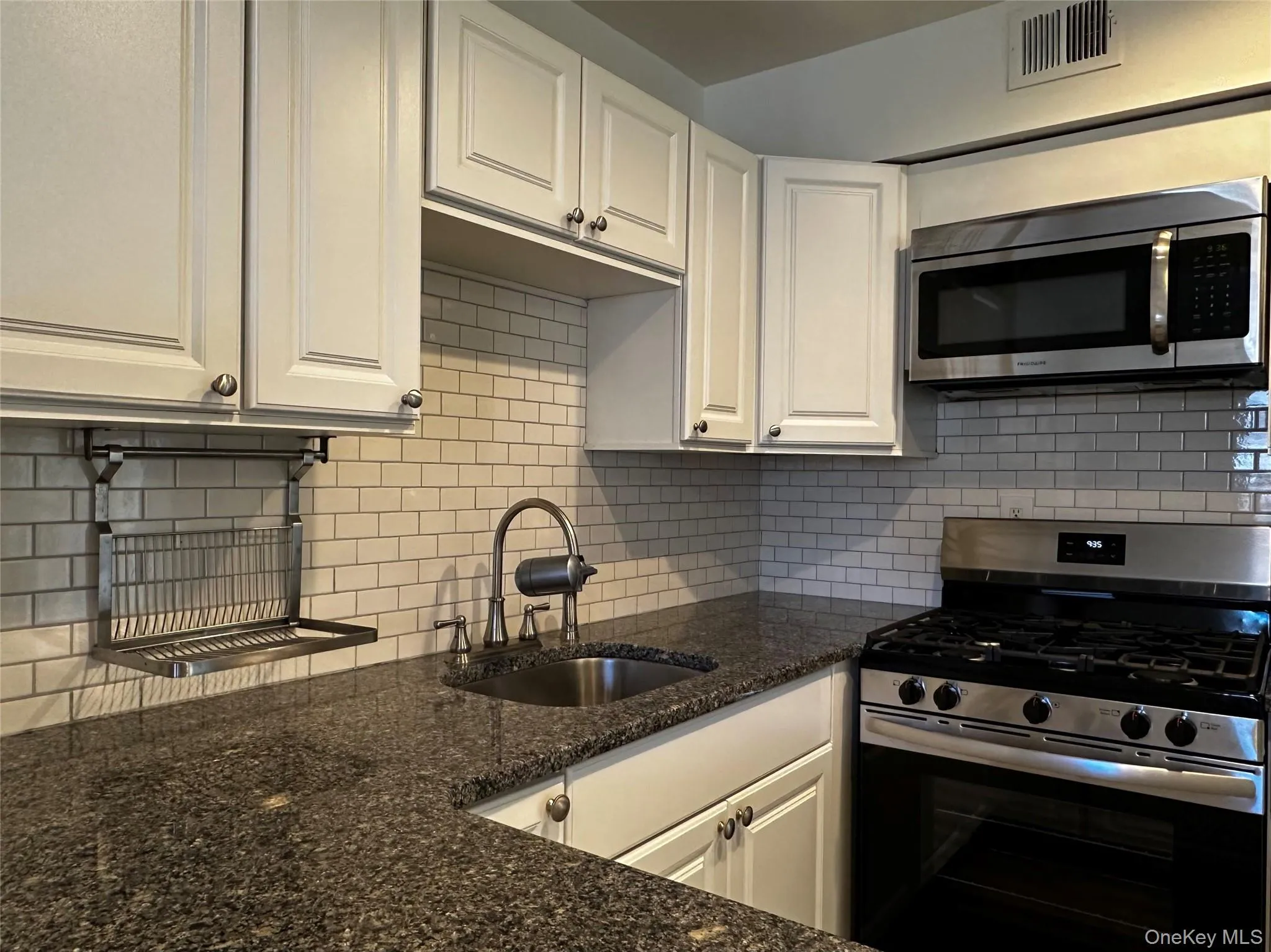 Kitchen with stainless steel appliances, white cabinets, and dark stone counters Kitchen with stainless steel appliances, white cabinets, and dark stone counters