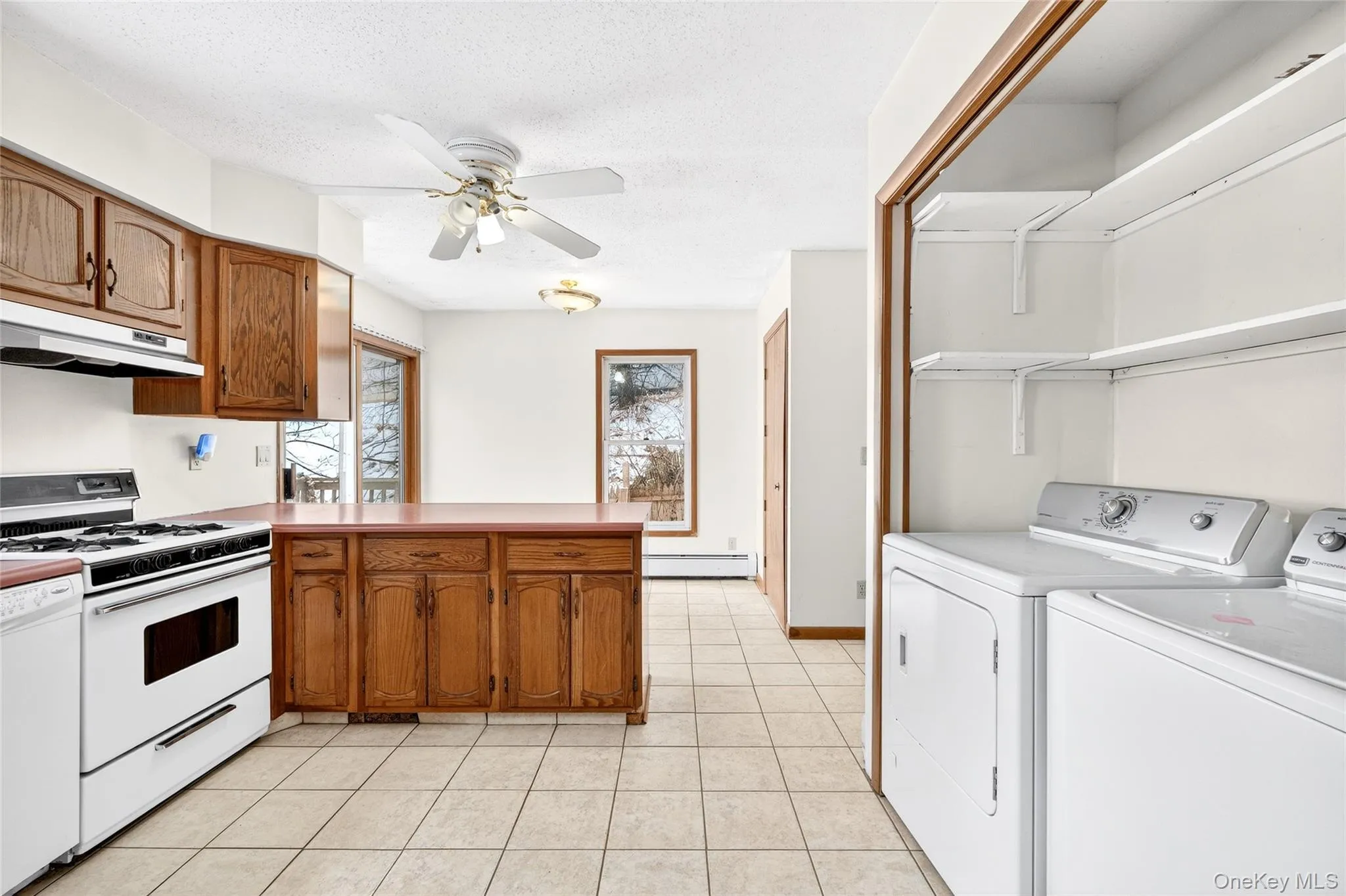 Kitchen with white appliances, a peninsula, open shelves, brown cabinets, and under cabinet range hood Kitchen with white appliances, a peninsula, open shelves, brown cabinets, and under cabinet range hood