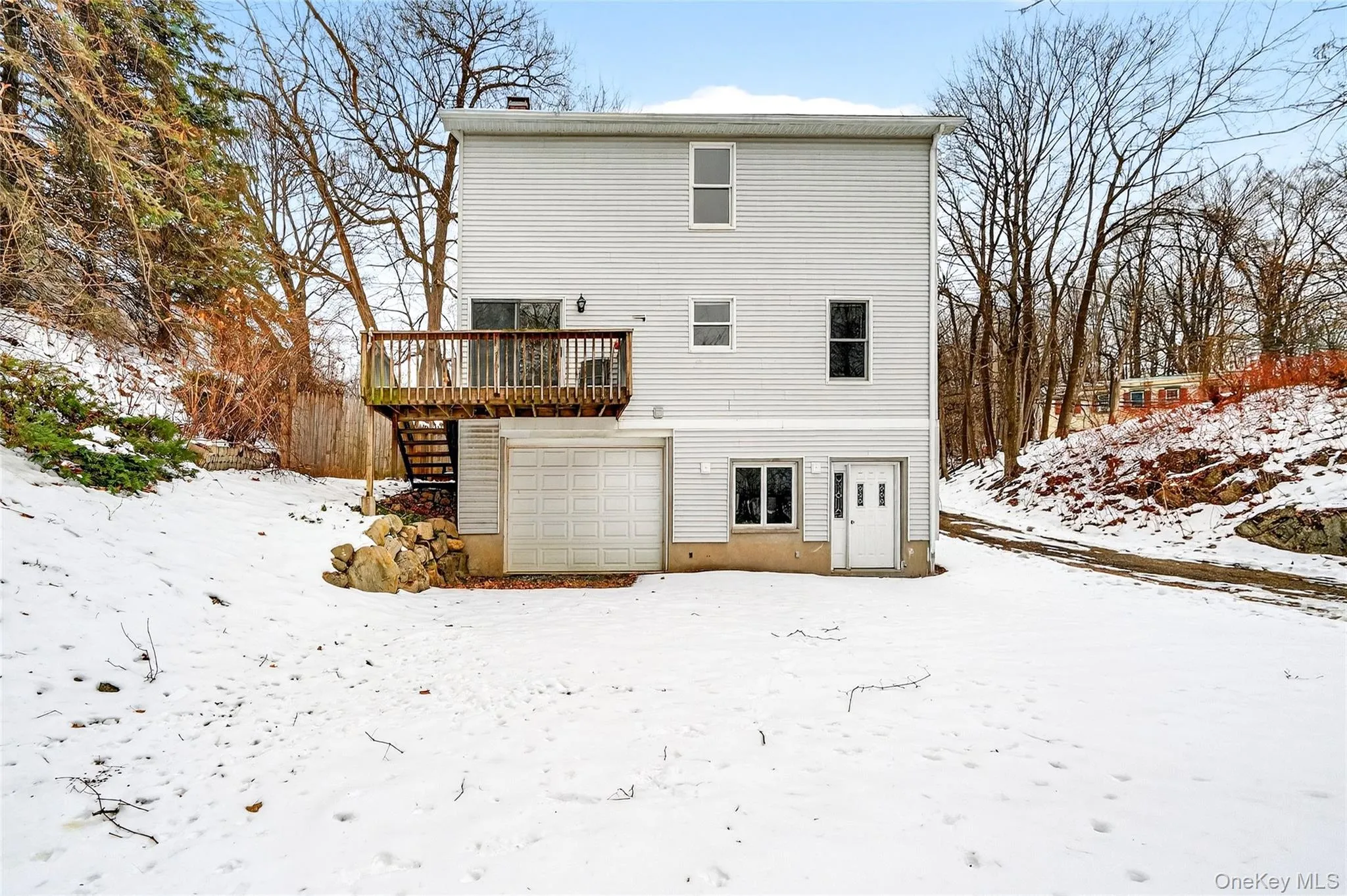 Snow covered rear of property with a chimney and a garage Snow covered rear of property with a chimney and a garage