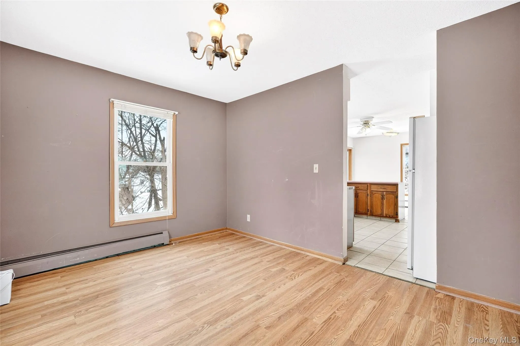 Dining room with a baseboard heating unit, a chandelier, light wood finished floors, and a ceiling fan Dining room with a baseboard heating unit, a chandelier, light wood finished floors, and a ceiling fan