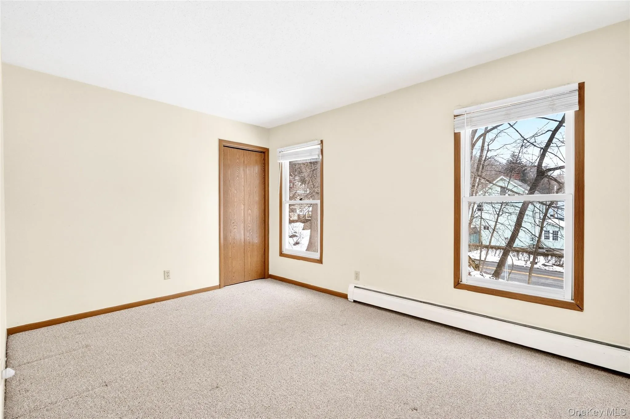 Spare room featuring a baseboard heating unit, plenty of natural light, and carpet floors Spare room featuring a baseboard heating unit, plenty of natural light, and carpet floors