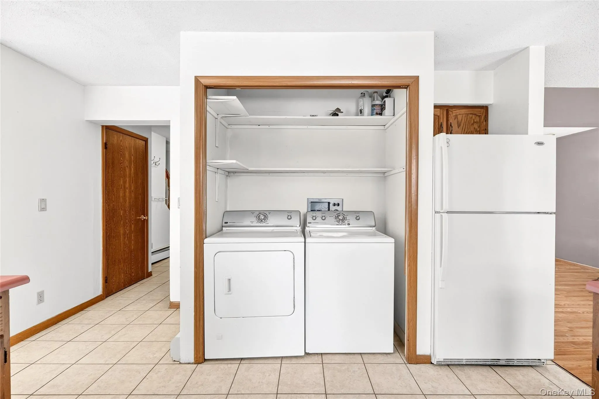 Laundry room featuring washer and dryer, a baseboard heating unit, and light tile patterned floors Laundry room featuring washer and dryer, a baseboard heating unit, and light tile patterned floors