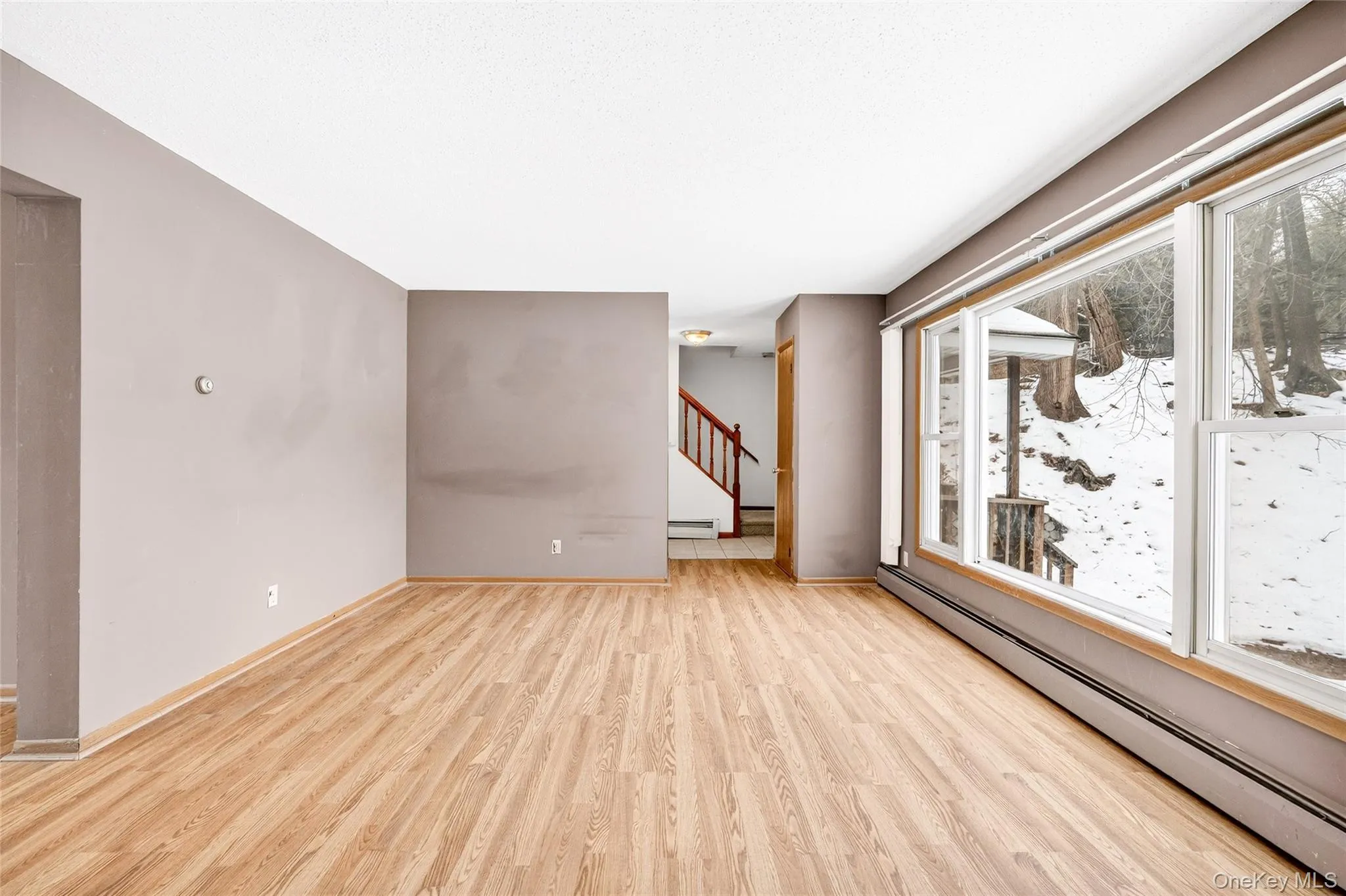 living room with a baseboard radiator, stairway, and light wood-style floors living room with a baseboard radiator, stairway, and light wood-style floors