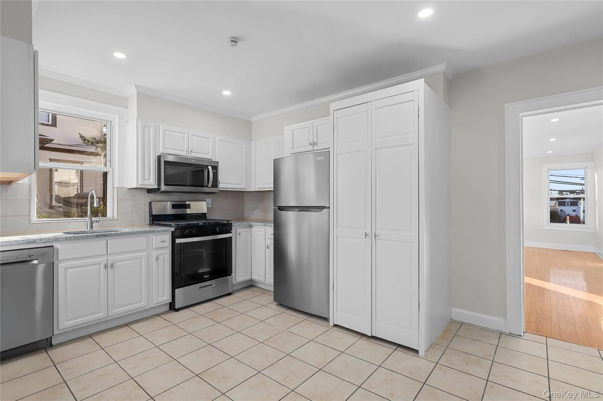Kitchen with healthy amount of natural light, white cabinetry, appliances with stainless steel finishes, recessed lighting, and ornamental molding Kitchen with healthy amount of natural light, white cabinetry, appliances with stainless steel finishes, recessed lighting, and ornamental molding