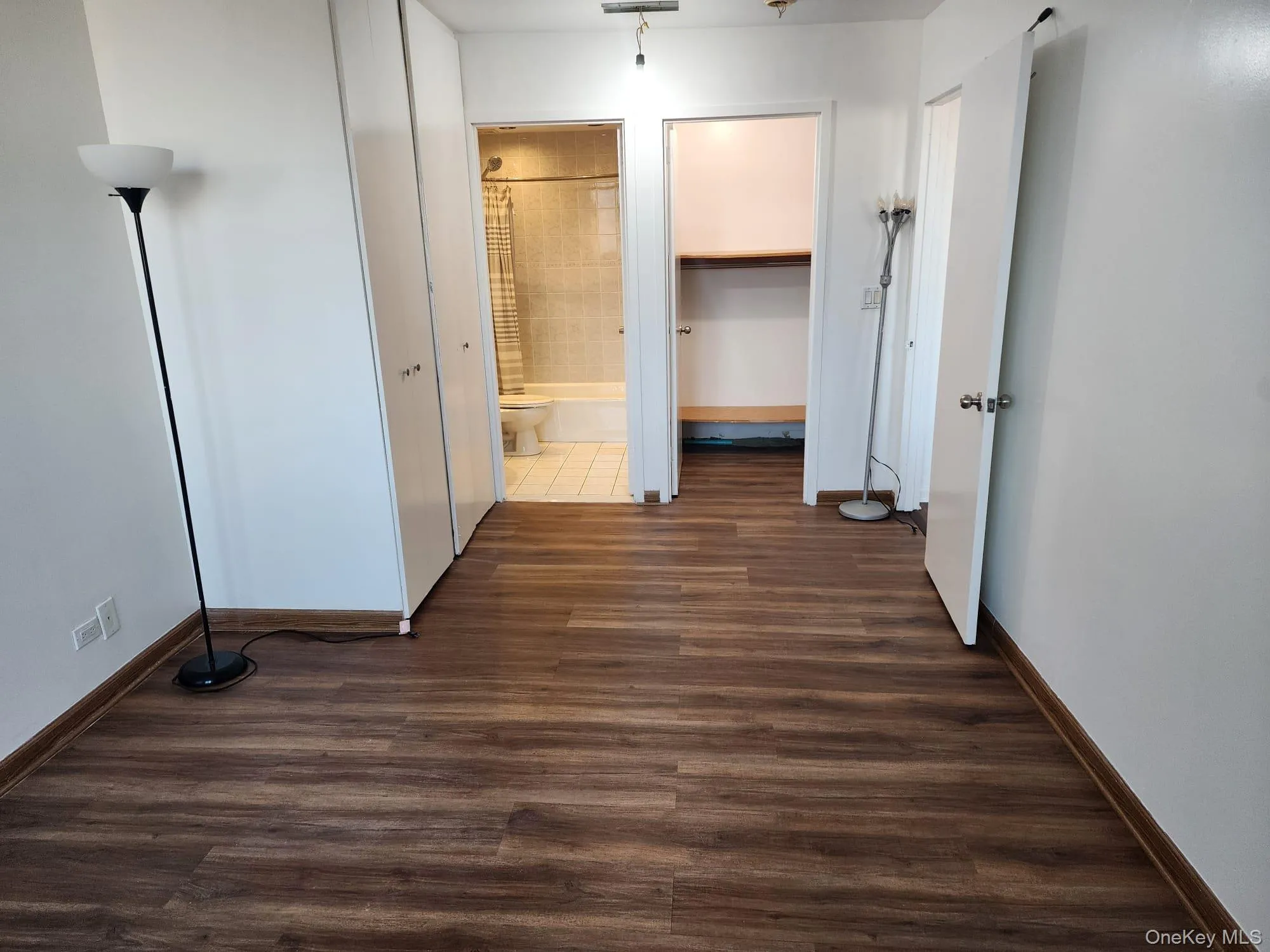 Corridor with dark wood-type flooring and baseboards Corridor with dark wood-type flooring and baseboards
