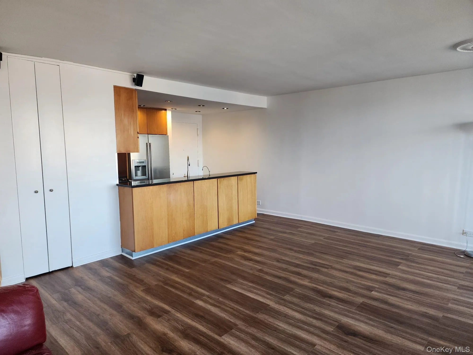 Kitchen featuring open floor plan, brown cabinets, a peninsula, and dark countertops Kitchen featuring open floor plan, brown cabinets, a peninsula, and dark countertops