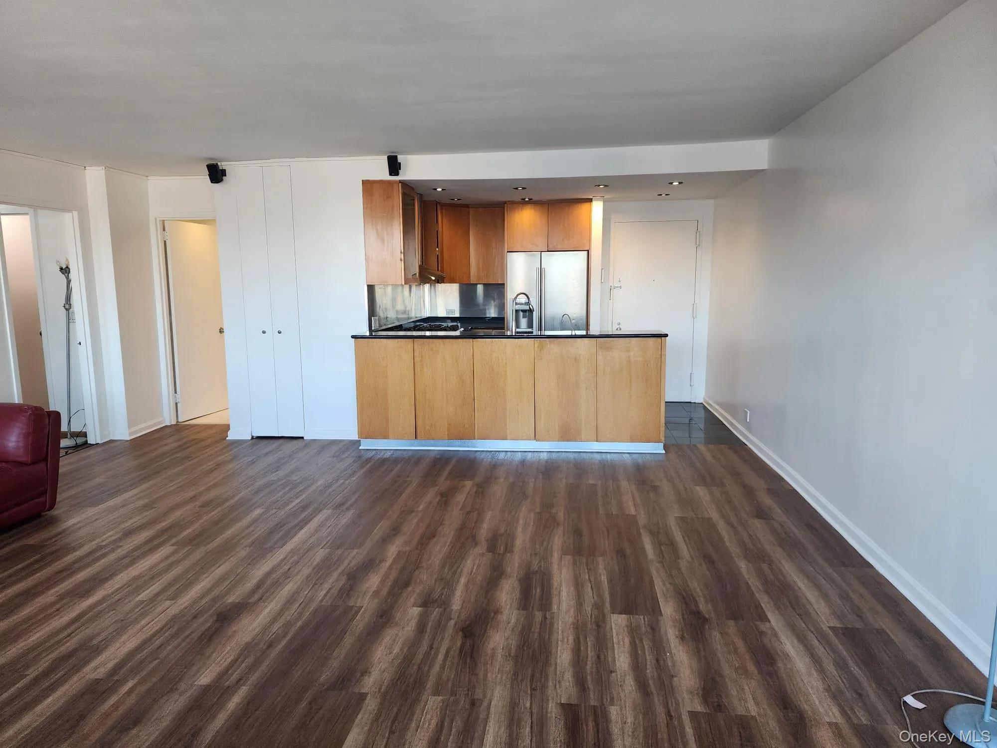 Kitchen featuring open floor plan, brown cabinetry, dark countertops, and a peninsula Kitchen featuring open floor plan, brown cabinetry, dark countertops, and a peninsula