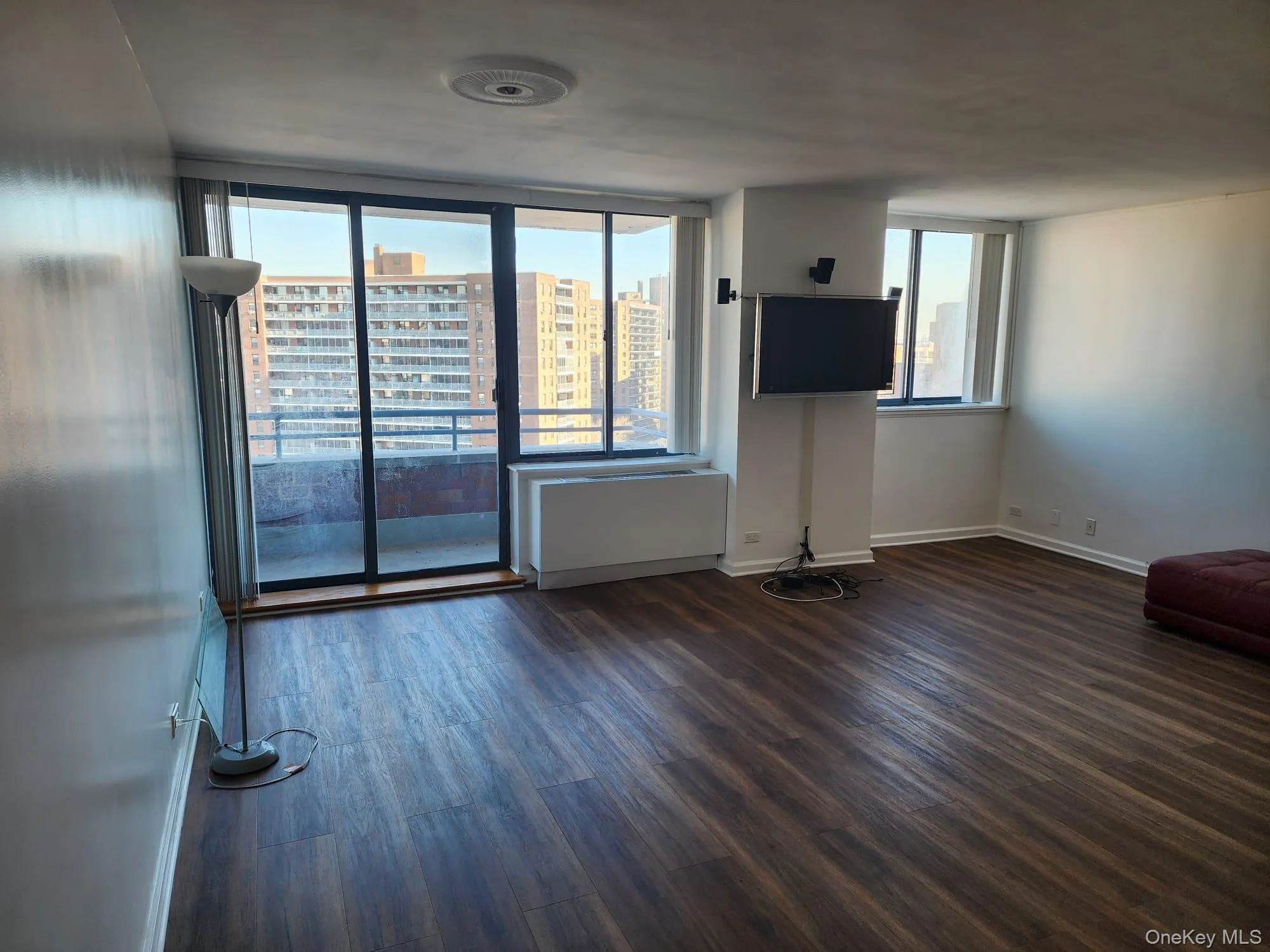 Unfurnished living room with dark wood-style flooring and healthy amount of natural light Unfurnished living room with dark wood-style flooring and healthy amount of natural light