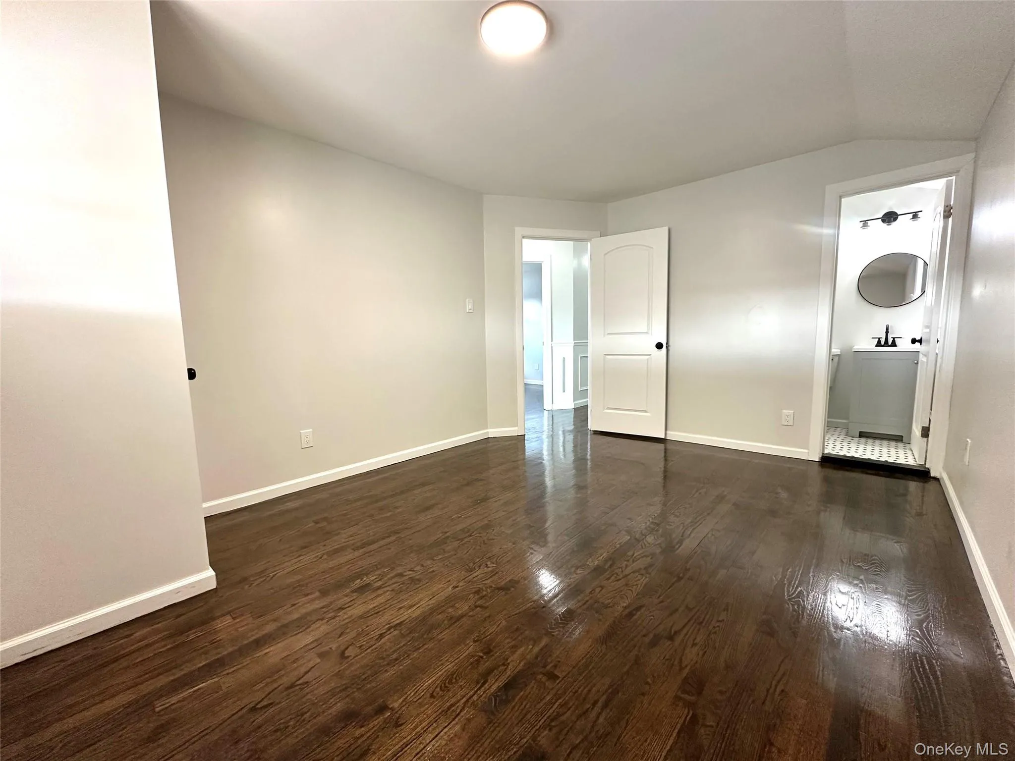 Spare room featuring dark wood-style floors and lofted ceiling Spare room featuring dark wood-style floors and lofted ceiling