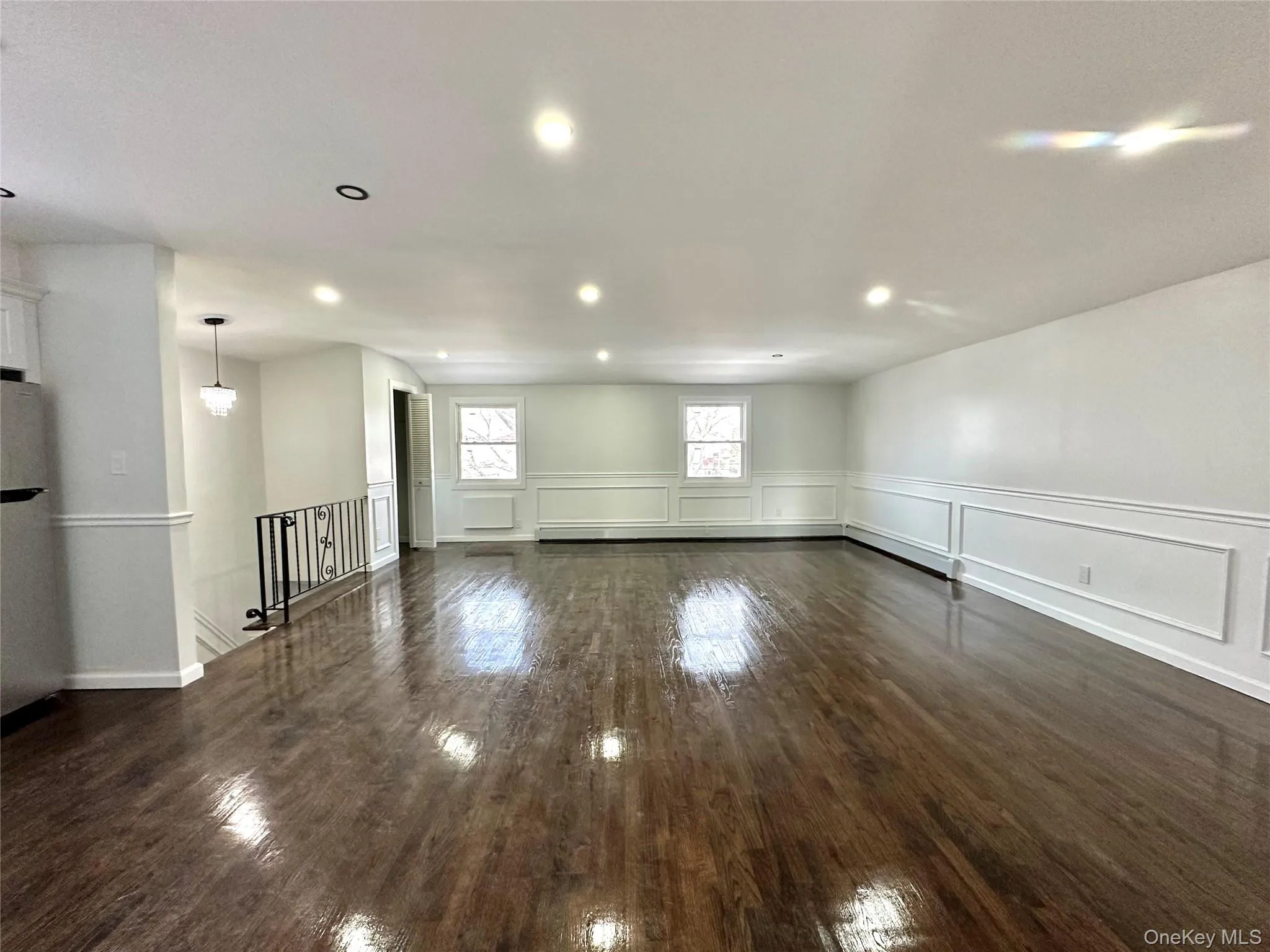 Unfurnished room featuring dark wood finished floors, recessed lighting, a decorative wall, wainscoting, and a baseboard heating unit Unfurnished room featuring dark wood finished floors, recessed lighting, a decorative wall, wainscoting, and a baseboard heating unit