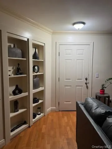 Doorway to outside featuring wood finished floors and ornamental molding Doorway to outside featuring wood finished floors and ornamental molding