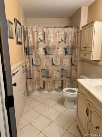 Bathroom featuring vanity, light tile patterned floors, and curtained shower Bathroom featuring vanity, light tile patterned floors, and curtained shower