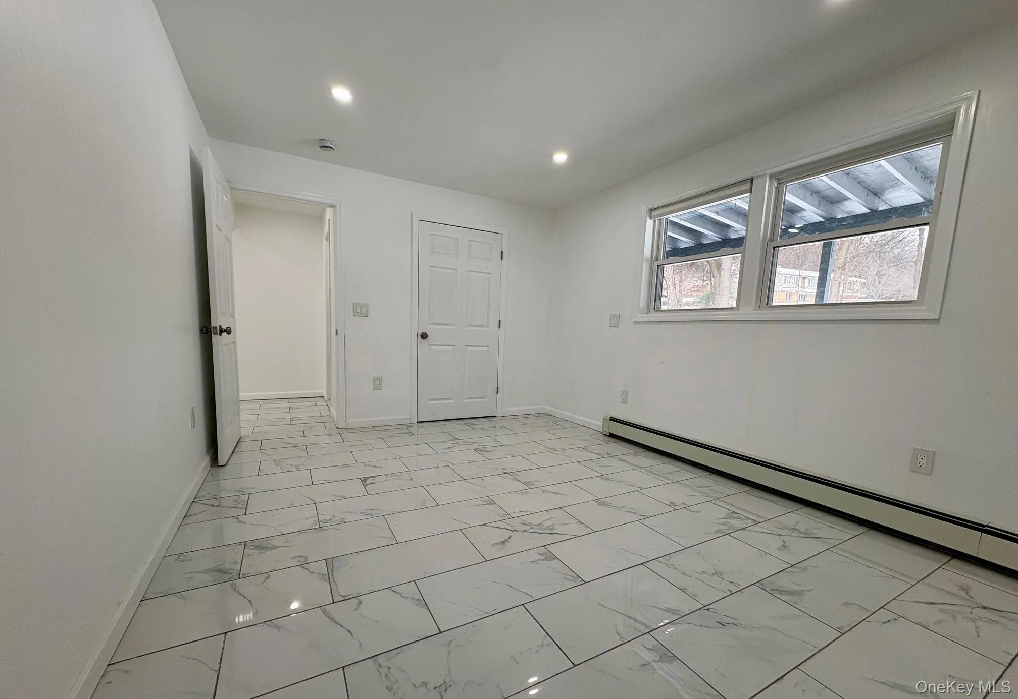 Unfurnished bedroom with light marble finish floors, baseboard heating, and recessed lighting Unfurnished bedroom with light marble finish floors, baseboard heating, and recessed lighting