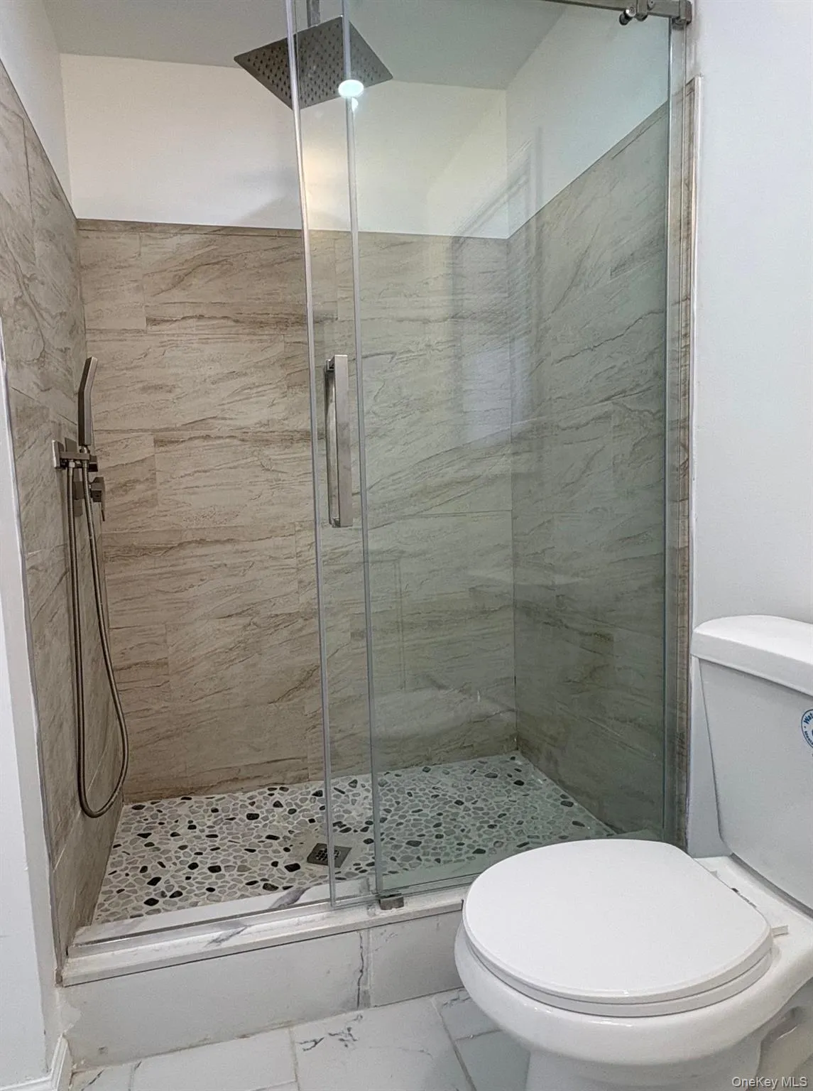Full bathroom with a shower stall and marble look tile flooring Full bathroom with a shower stall and marble look tile flooring