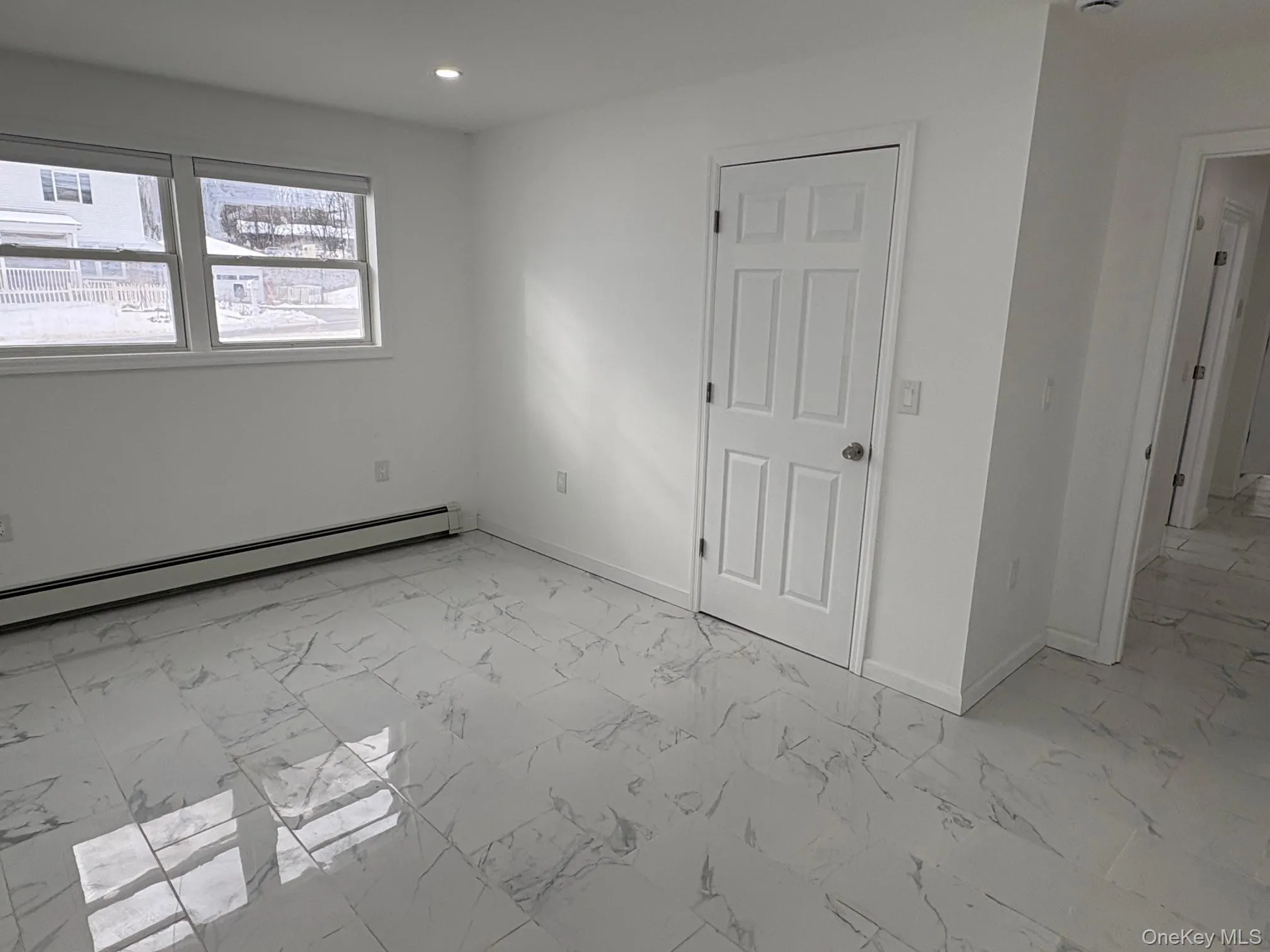 Unfurnished room with light marble finish floors, baseboard heating, and recessed lighting Unfurnished room with light marble finish floors, baseboard heating, and recessed lighting