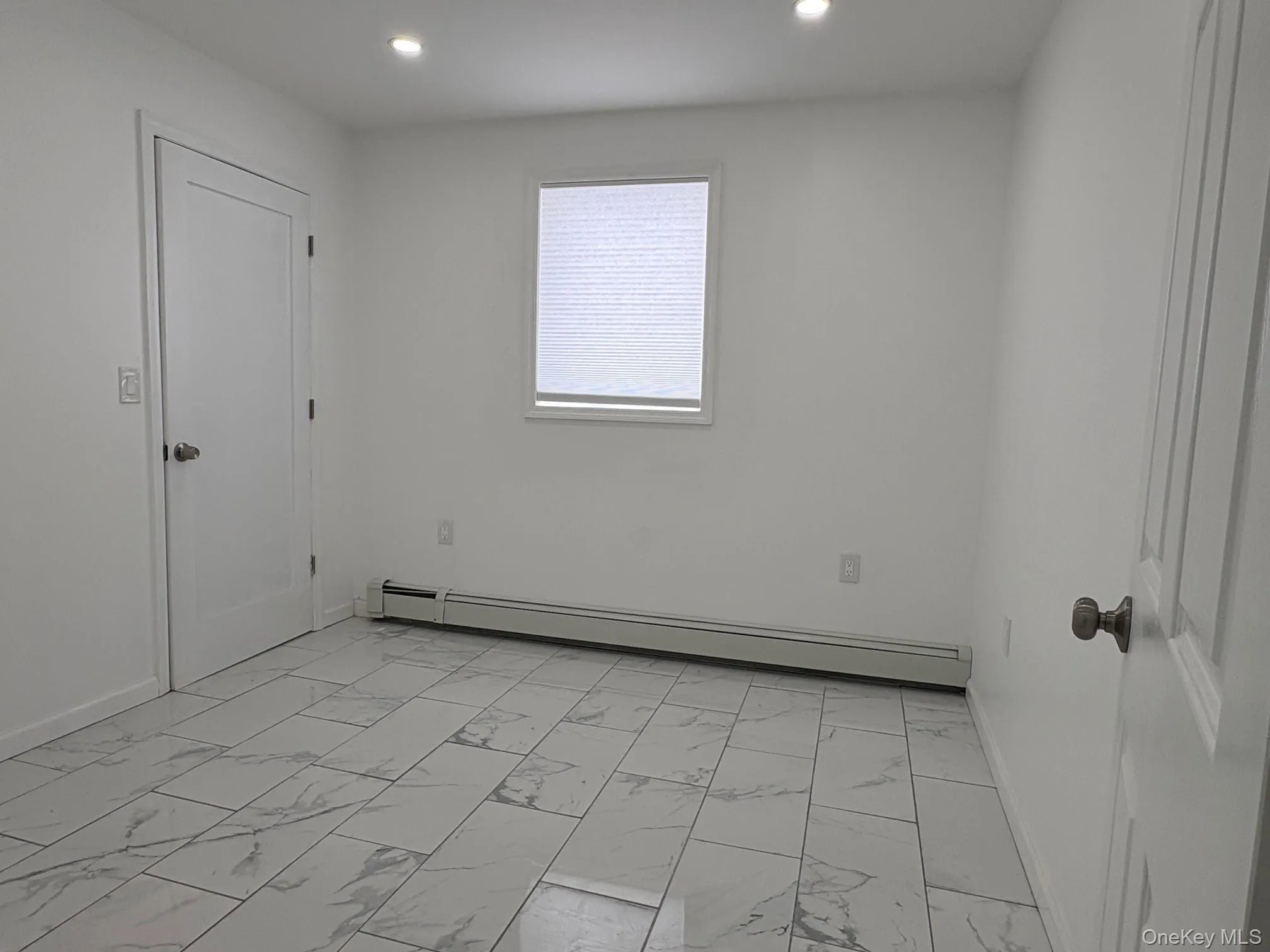 Unfurnished room with a baseboard heating unit, recessed lighting, and light marble finish floors Unfurnished room with a baseboard heating unit, recessed lighting, and light marble finish floors