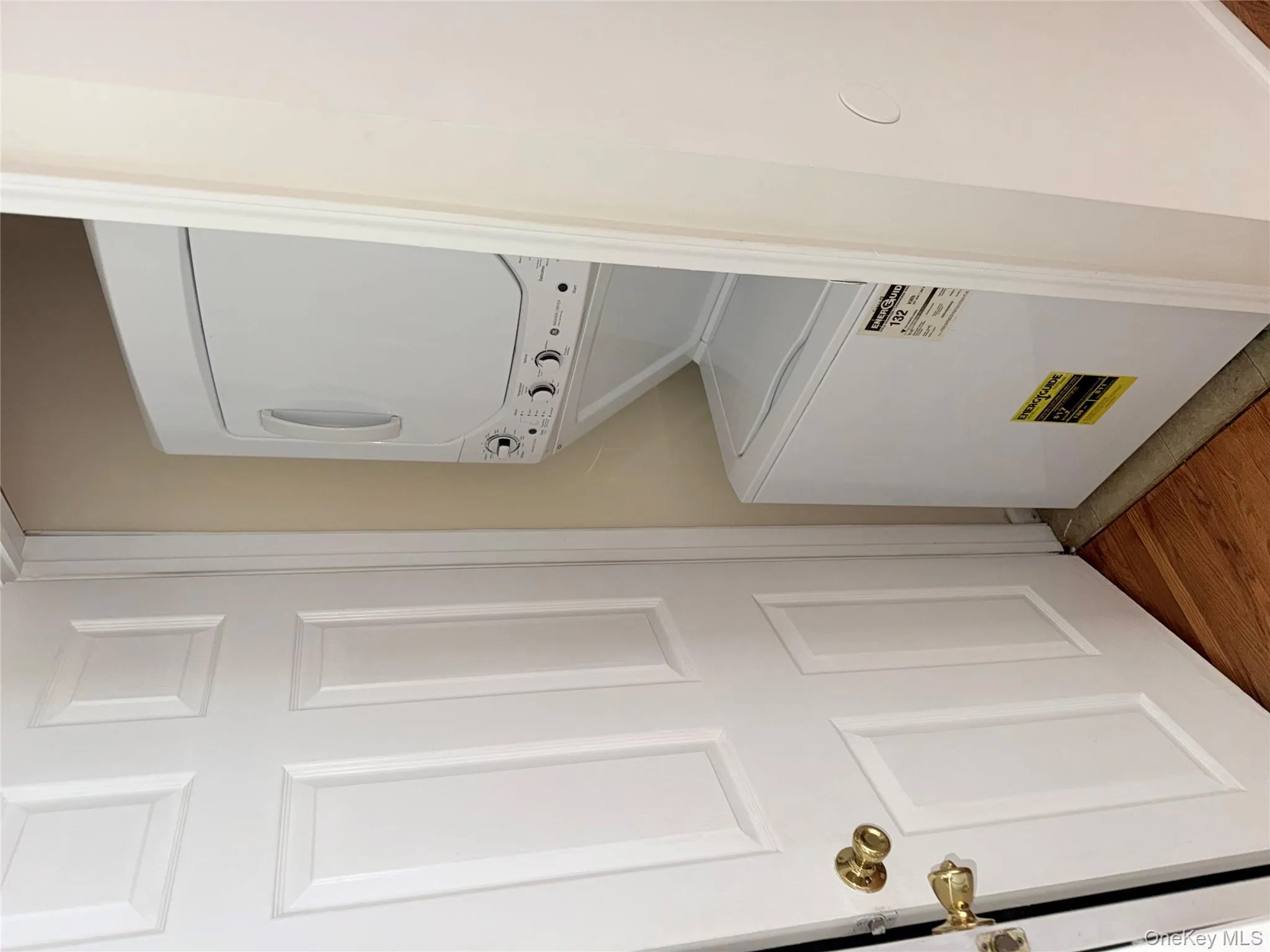 Washroom featuring estacked washer and dryer and wood finished floors Washroom featuring estacked washer and dryer and wood finished floors