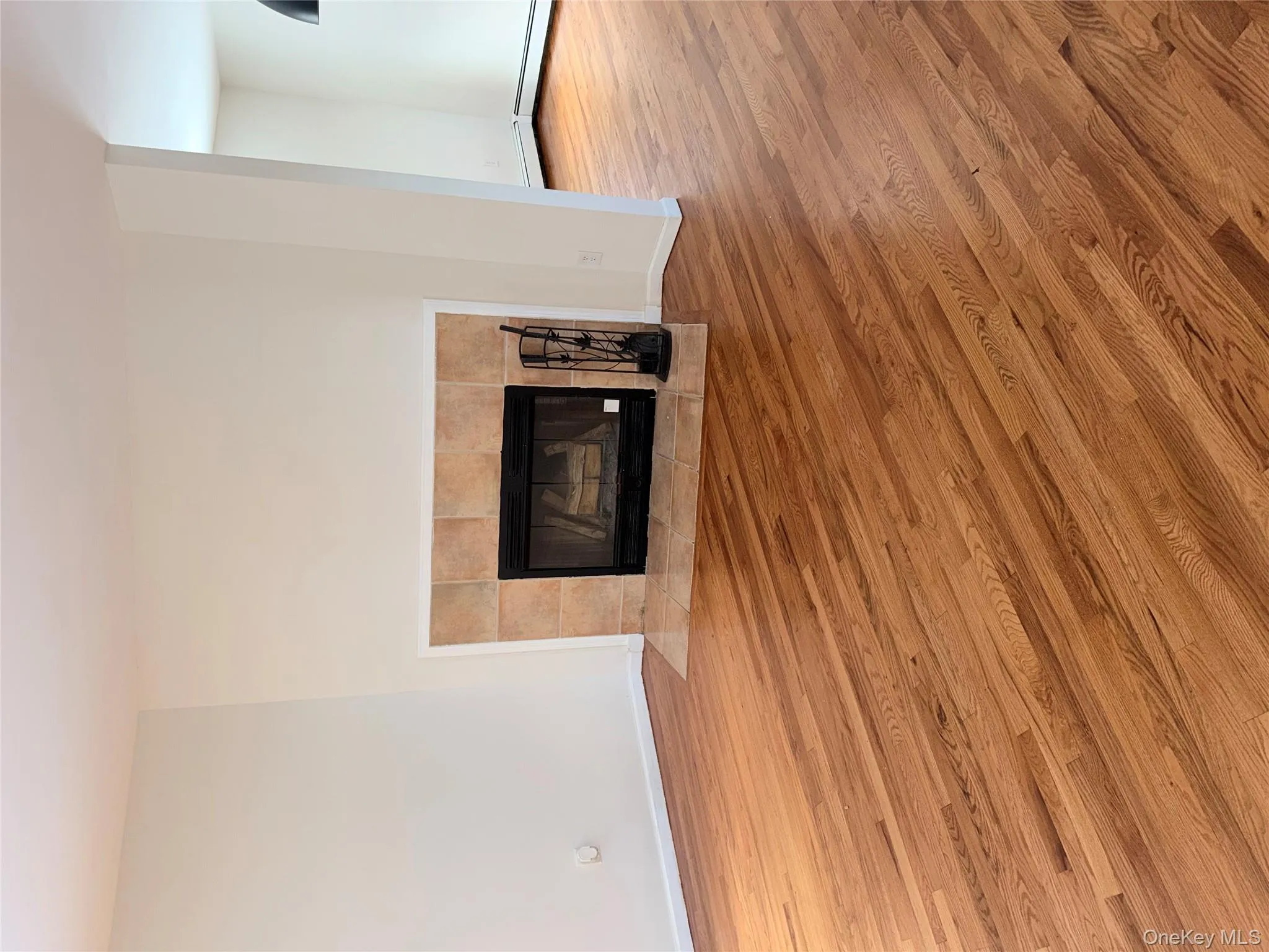 Detailed view of a tiled fireplace and wood finished floors Detailed view of a tiled fireplace and wood finished floors