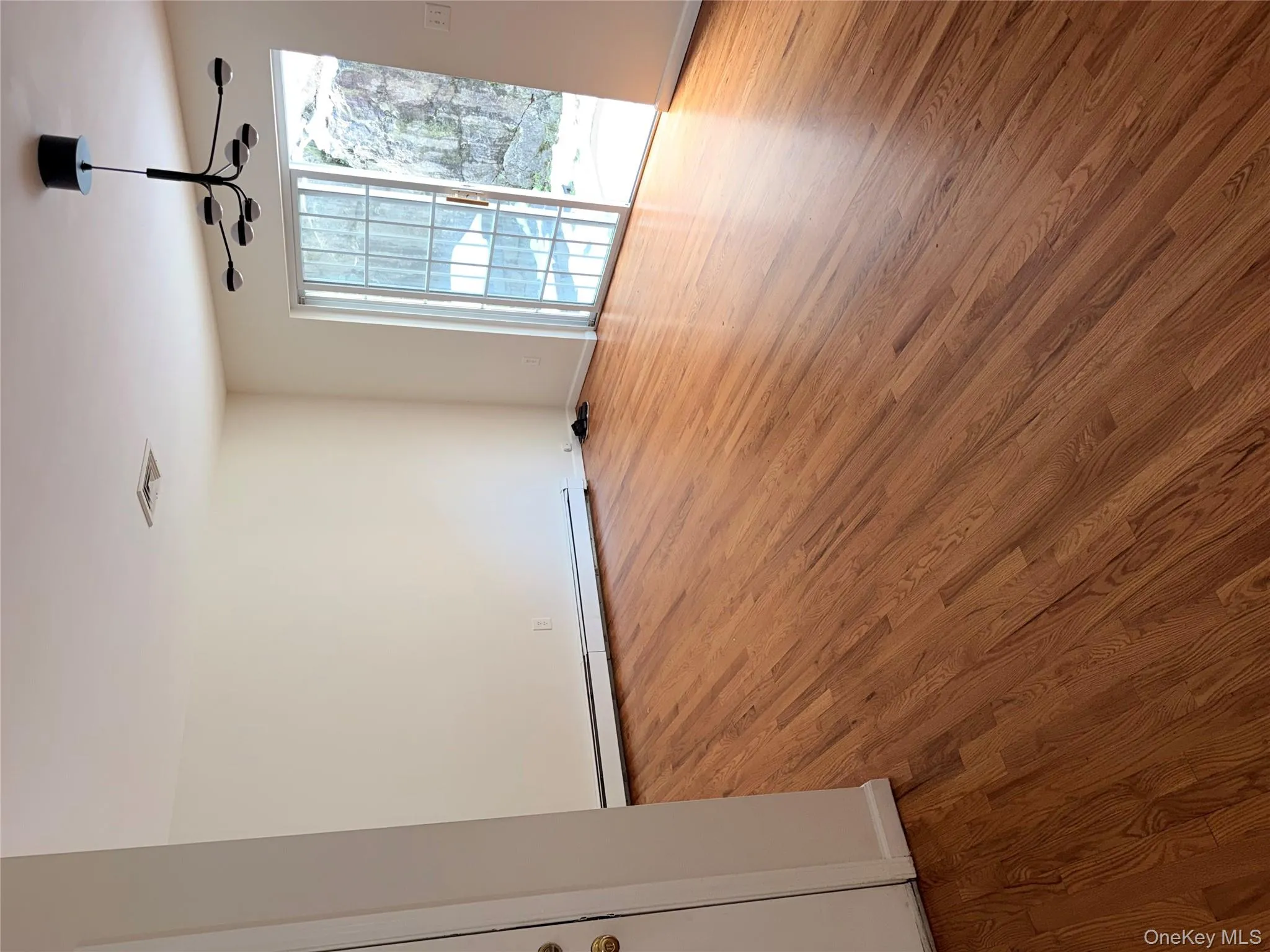 Unfurnished room with baseboard heating, light wood-style flooring, and a chandelier Unfurnished room with baseboard heating, light wood-style flooring, and a chandelier