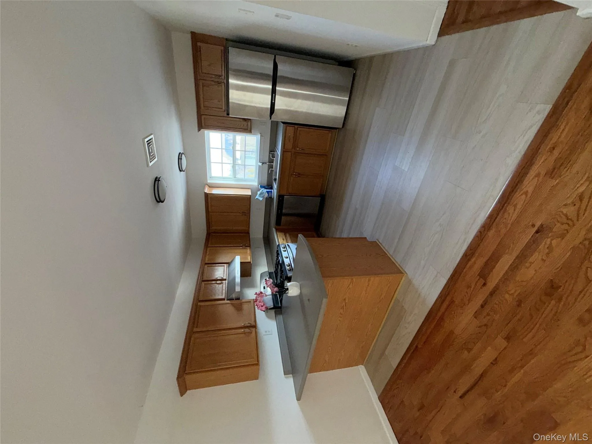 Kitchen with brown cabinetry, a peninsula, fridge, light wood-type flooring, and range Kitchen with brown cabinetry, a peninsula, fridge, light wood-type flooring, and range