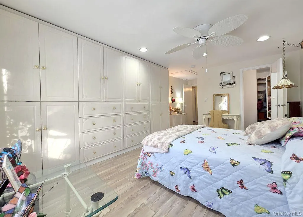 Bedroom featuring light wood-style floors, a ceiling fan, recessed lighting, and a spacious closet Bedroom featuring light wood-style floors, a ceiling fan, recessed lighting, and a spacious closet