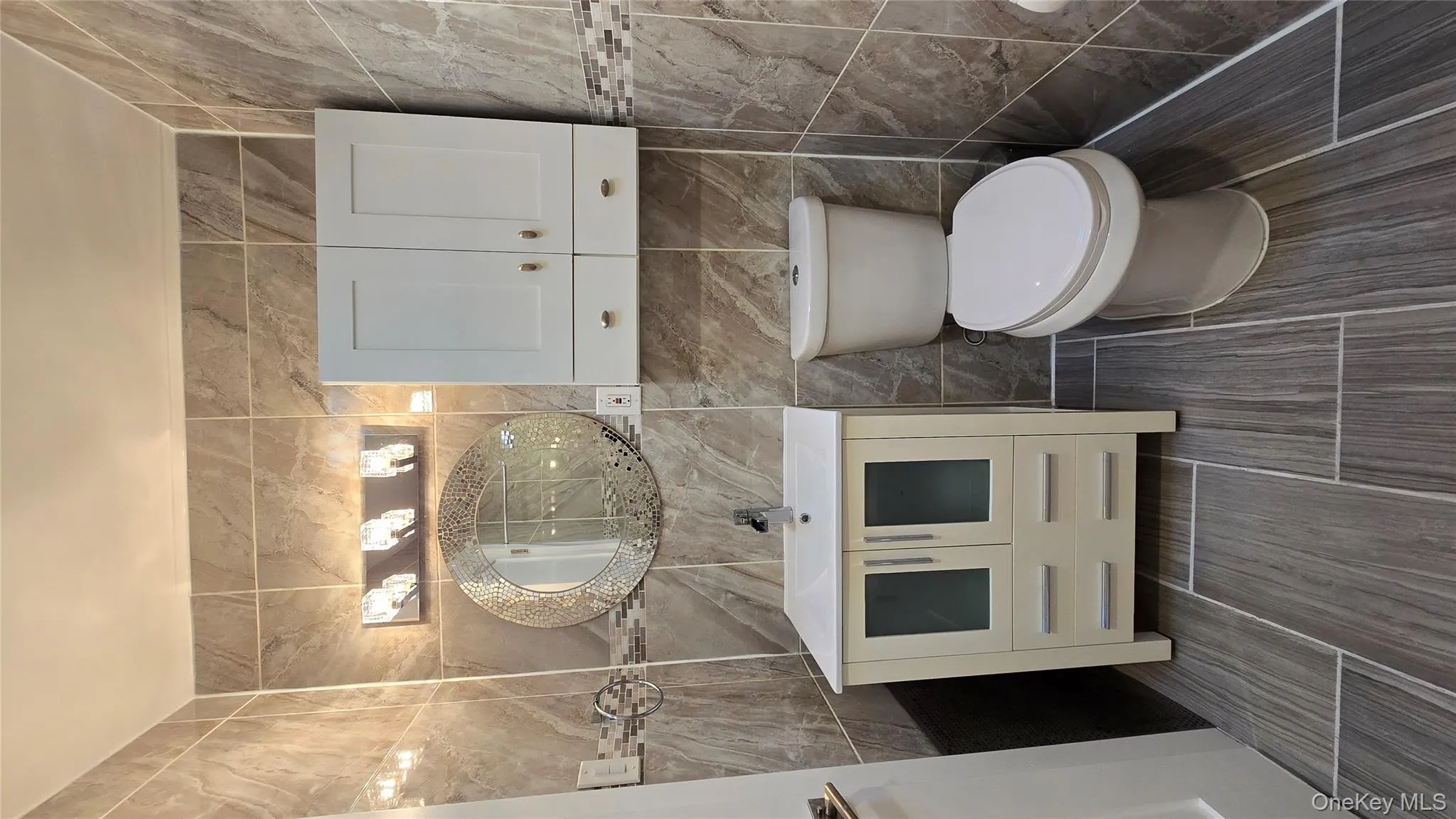 Bathroom featuring vanity, tile walls, and a shower Bathroom featuring vanity, tile walls, and a shower