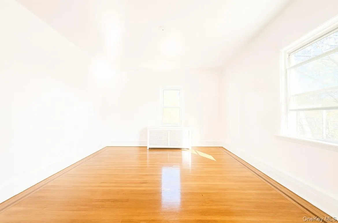 Empty room with light wood finished floors and radiator heating unit Empty room with light wood finished floors and radiator heating unit