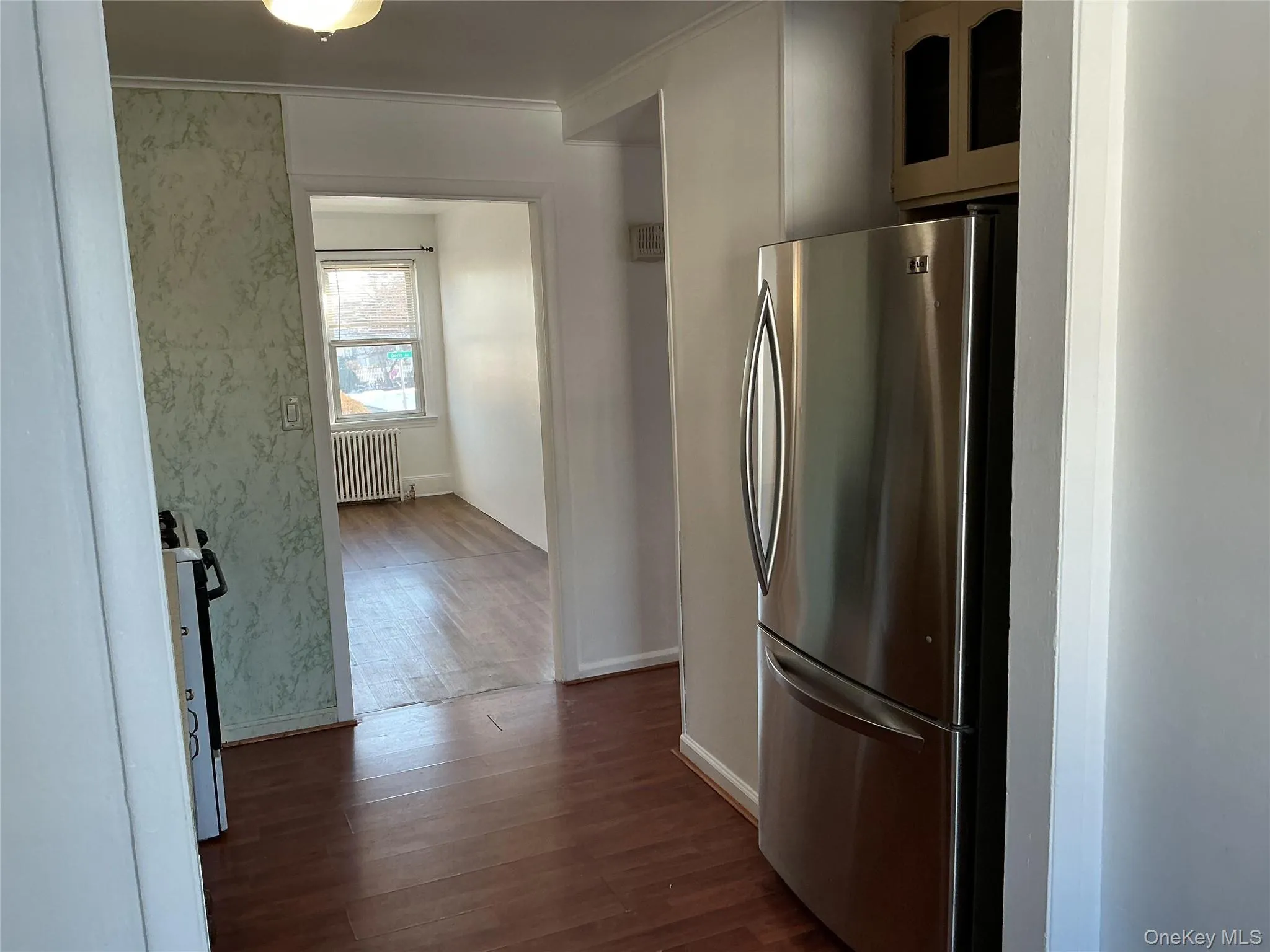 Kitchen featuring freestanding refrigerator, dark wood-type flooring, white stove, radiator, and crown molding Kitchen featuring freestanding refrigerator, dark wood-type flooring, white stove, radiator, and crown molding