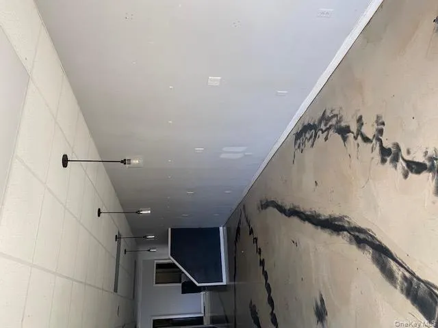 Unfurnished living room featuring a drop ceiling and concrete flooring Unfurnished living room featuring a drop ceiling and concrete flooring