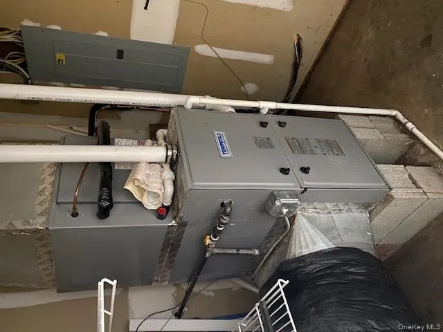 Utility room featuring heating unit and electric panel Utility room featuring heating unit and electric panel
