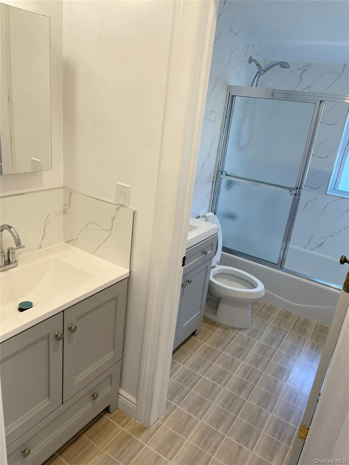 Full bath featuring two vanities and shower / bath combination with glass door Full bath featuring two vanities and shower / bath combination with glass door