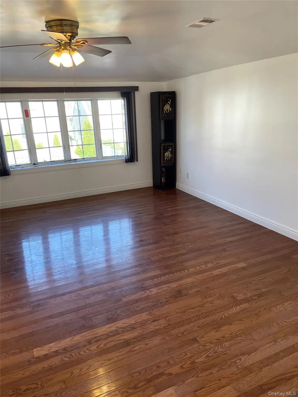 Empty room with dark wood-type flooring and ceiling fan Empty room with dark wood-type flooring and ceiling fan