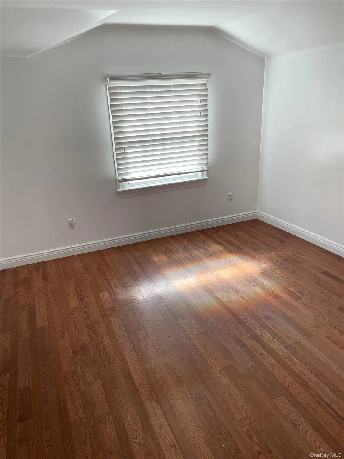 Empty room featuring wood-type flooring and vaulted ceiling Empty room featuring wood-type flooring and vaulted ceiling
