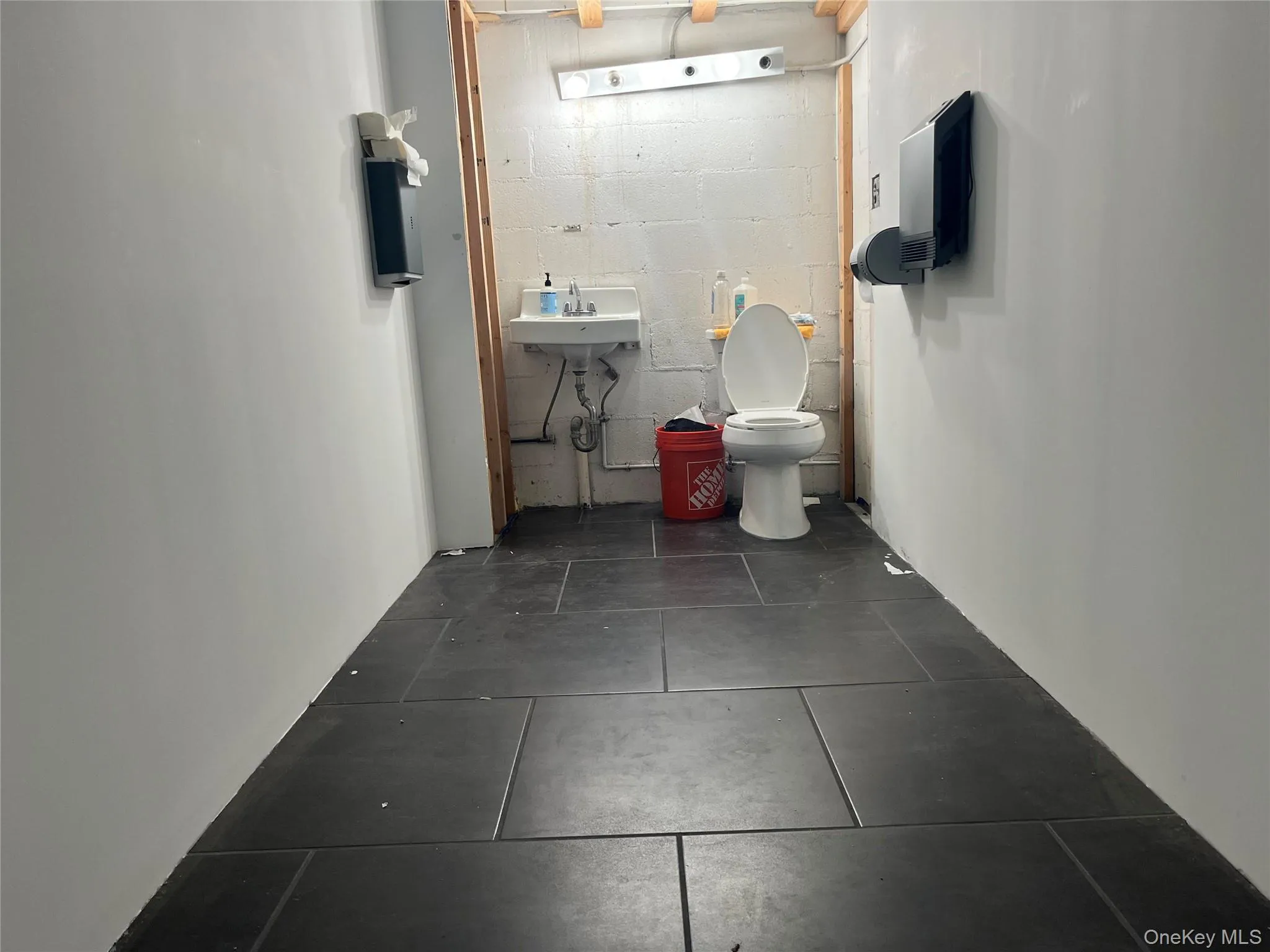 Half bath featuring concrete block wall and toilet Half bath featuring concrete block wall and toilet