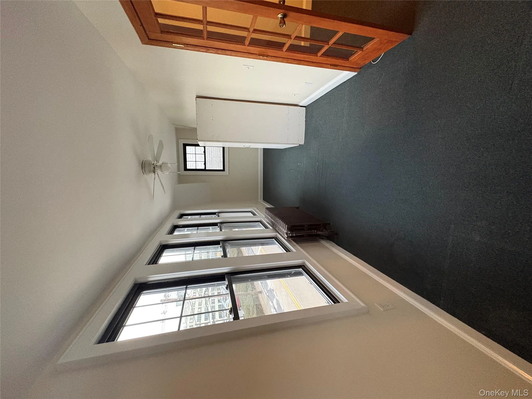 Spare room featuring dark carpet, a ceiling fan, and radiator heating unit Spare room featuring dark carpet, a ceiling fan, and radiator heating unit