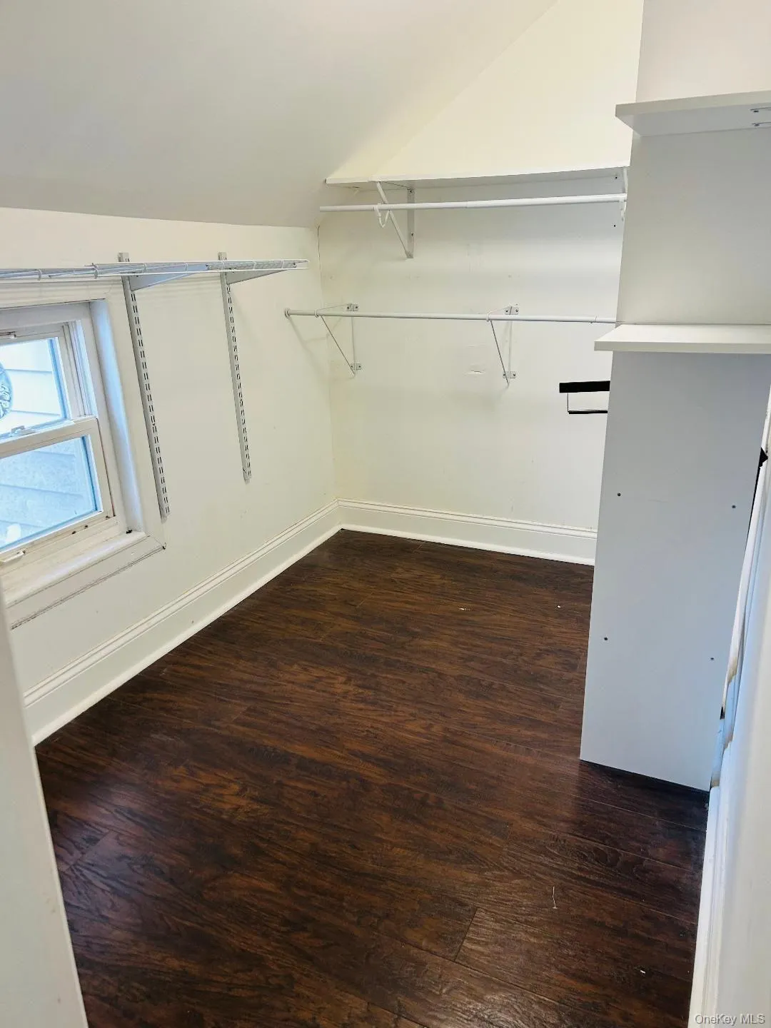 Walk in closet featuring dark wood-style flooring and lofted ceiling Walk in closet featuring dark wood-style flooring and lofted ceiling