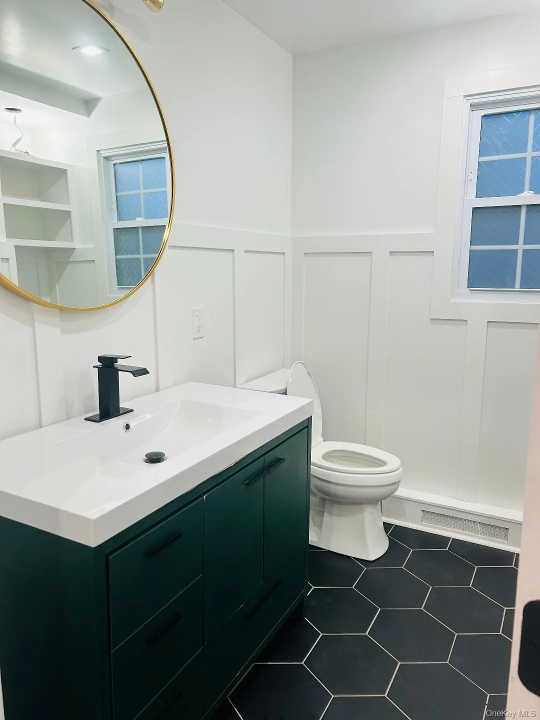 Half bathroom featuring a decorative wall, vanity, a wainscoted wall, and dark tile patterned flooring Half bathroom featuring a decorative wall, vanity, a wainscoted wall, and dark tile patterned flooring