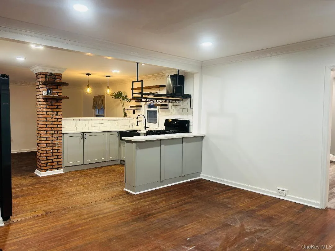 Bar area with gray cabinets, dark wood-type flooring, crown molding, decorative light fixtures, and light countertops Bar area with gray cabinets, dark wood-type flooring, crown molding, decorative light fixtures, and light countertops